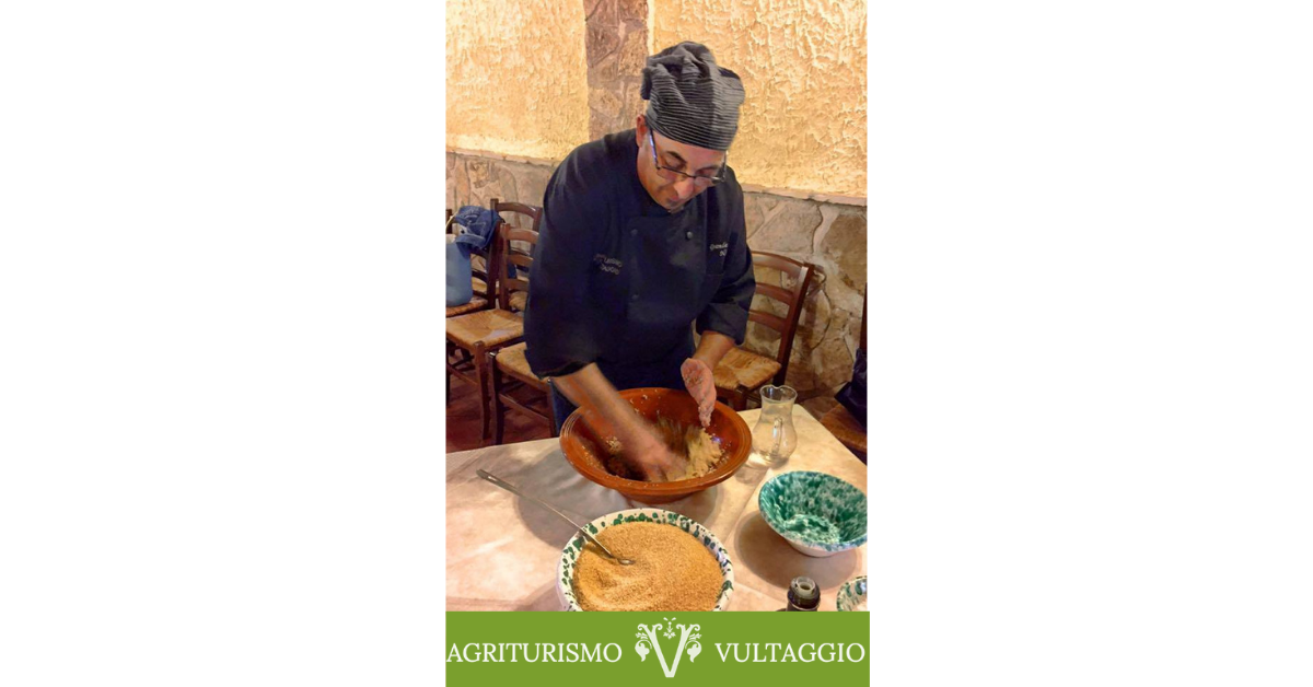 Nino Buscaino in primo piano che sta preparando il couscous incocciando la semola all'interno del lemmo durante un cooking show.